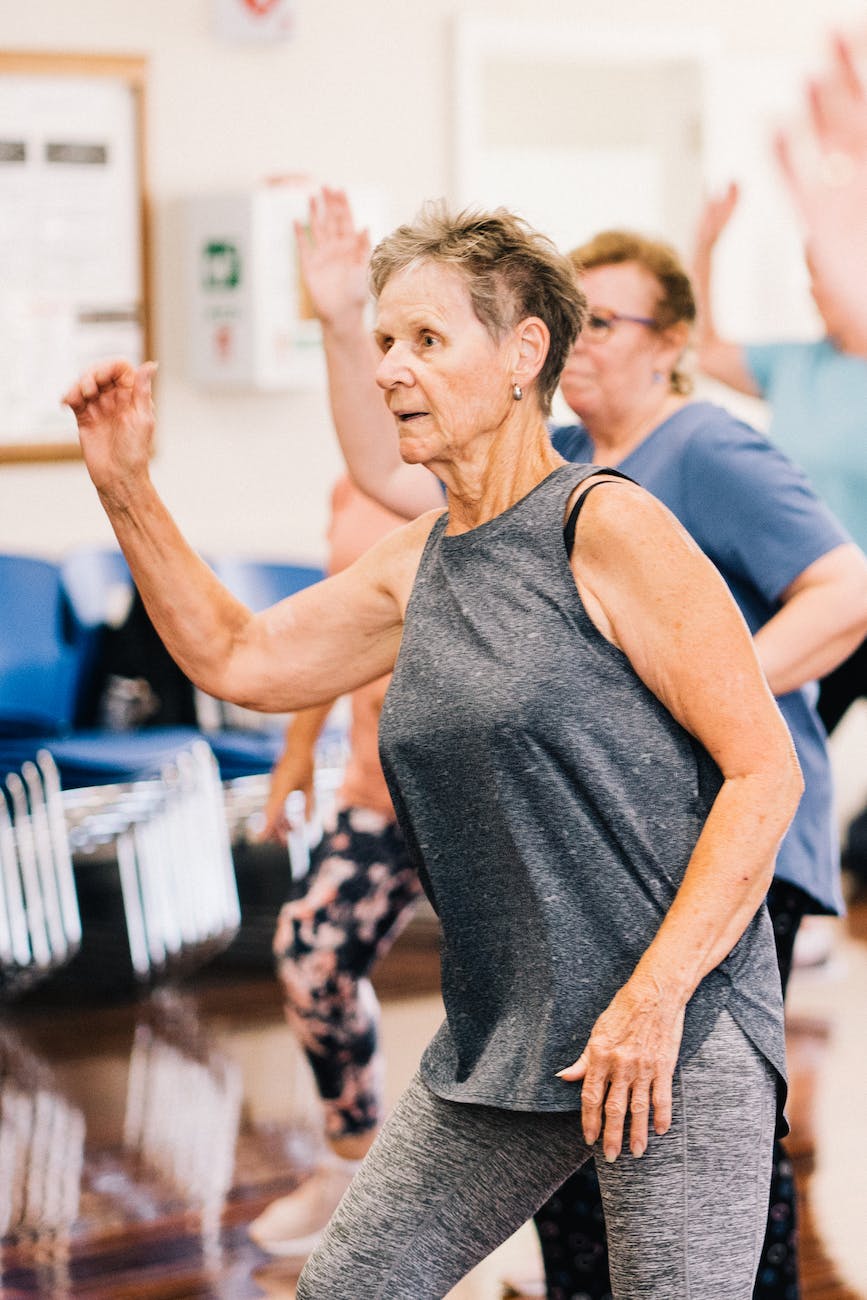 elderly woman in gray tank top and leggings exercising